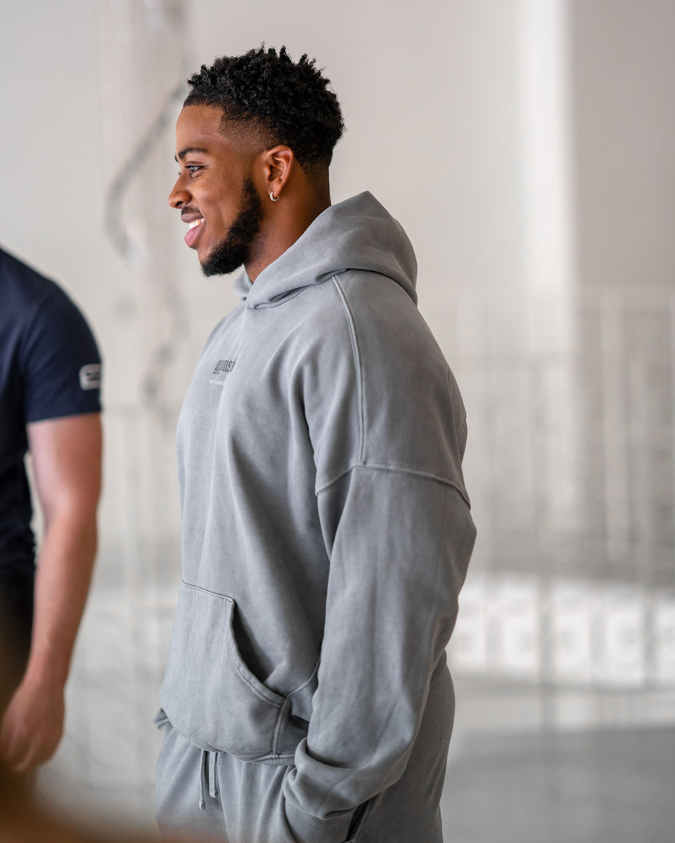 Picture of the coach in a grey hoodie, smiling, looking sideways.